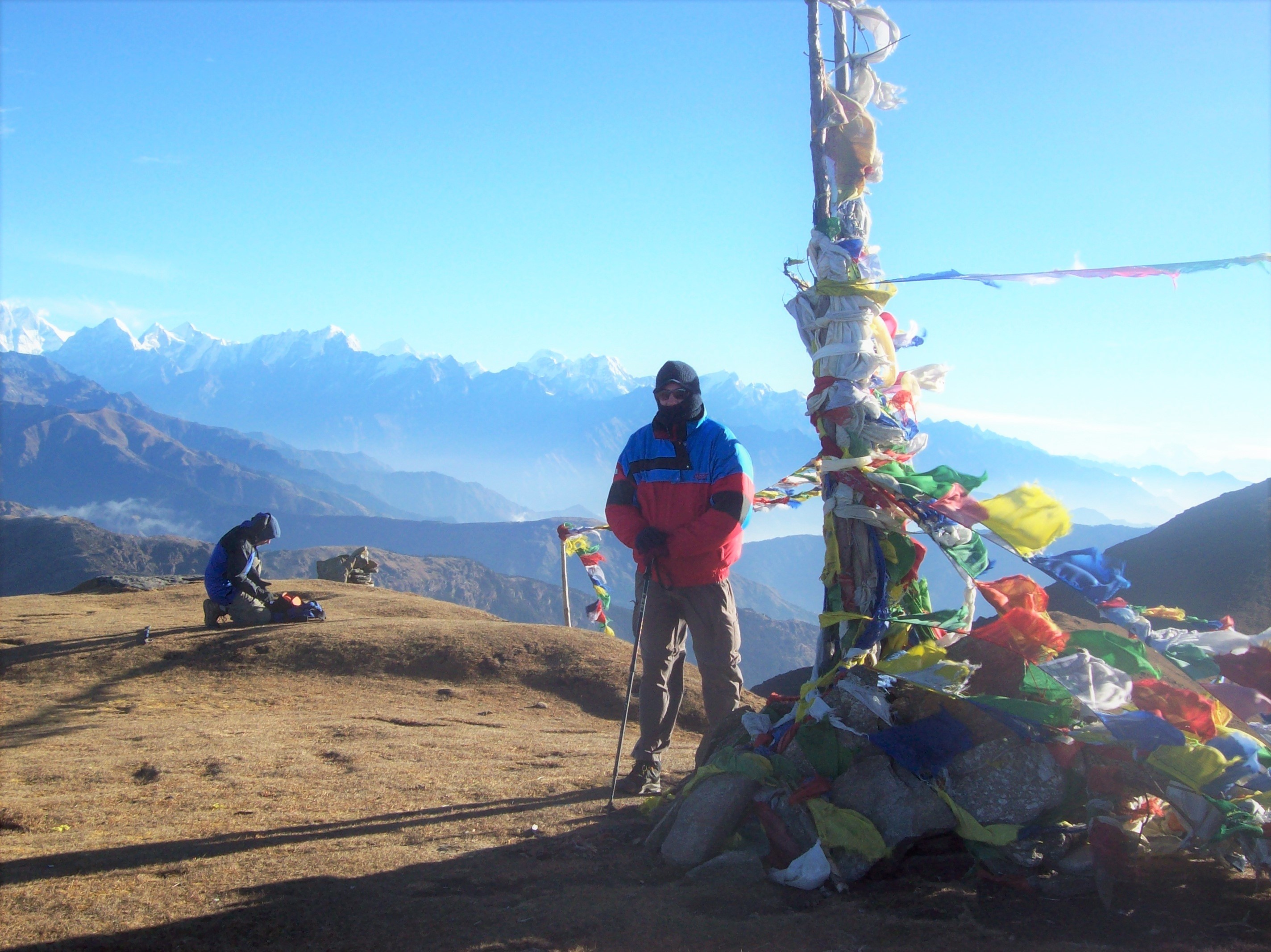 Man standing near prayer flags at a mountain summit