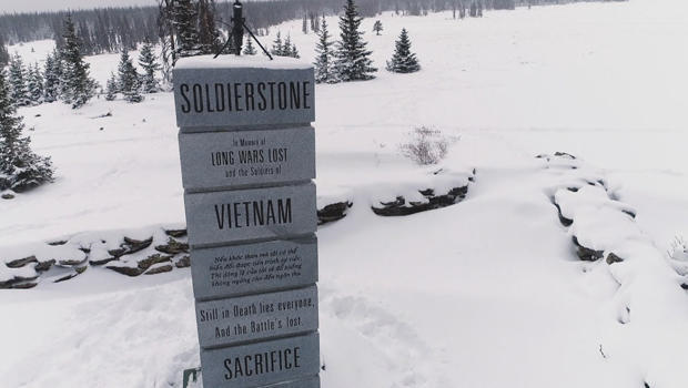 Memorial to people who died in the Vietnam War standing in a snowy field with a few evergreen trees. 