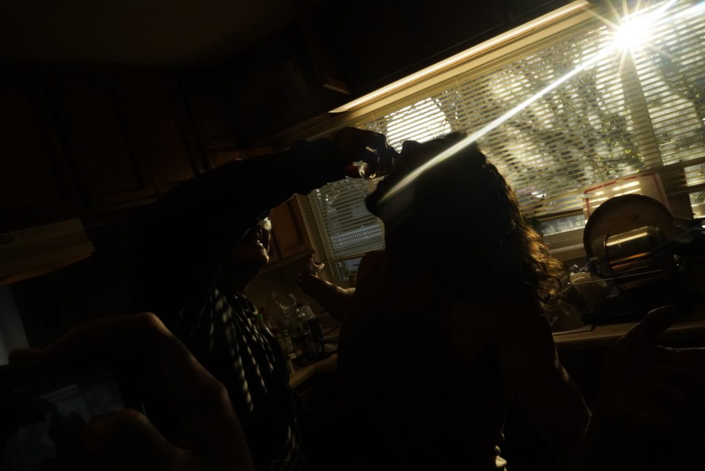 Young man and young woman in a room in front of a window with open blinds and the sun entering.