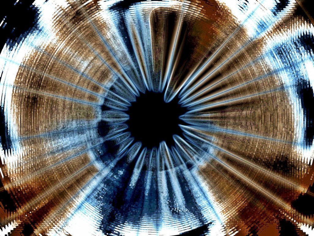 Image of something blue and brown that's out of focus and unidentifiable, looks like an eyeball with a brown and blue iris and a black pupil. Image is photographically altered to have less focus on the edges, as if the photographer zoomed out with the lens. 