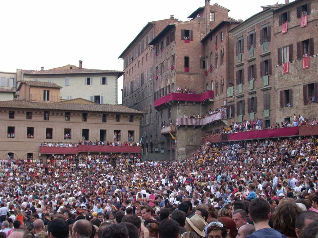 Lots of people in Siena in front of old buildings getting ready to watch the palio!