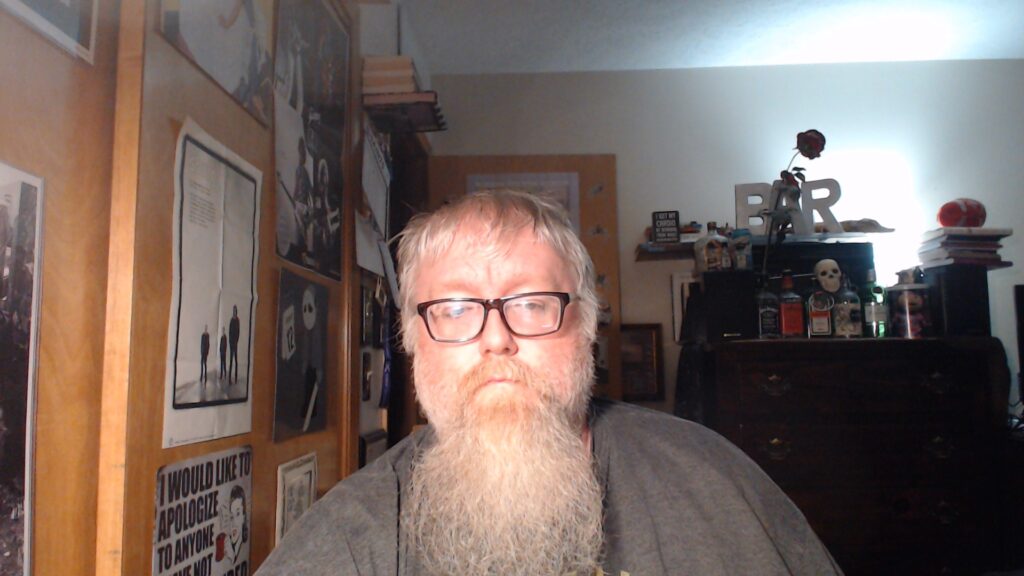 Middle aged guy with a big beard standing in a bedroom