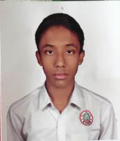 Young South Asian boy with a serious face and a white collared shirt with an emblem on the right breast. He has short brown hair and brown eyes.