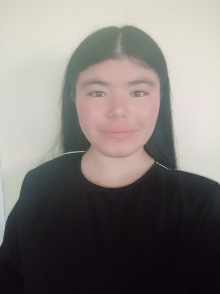 Young Central Asian girl with dark black hair and brown eyes and a black tee shirt. 