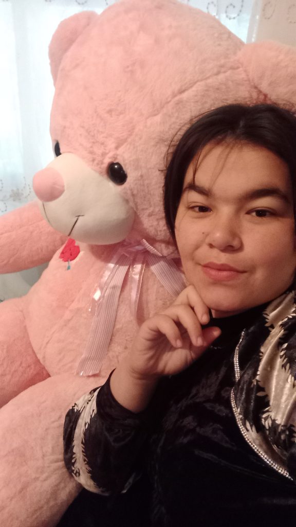 Young East Asian girl with dark black straight hair, a black and white velvet blouse, and a pink teddy bear.