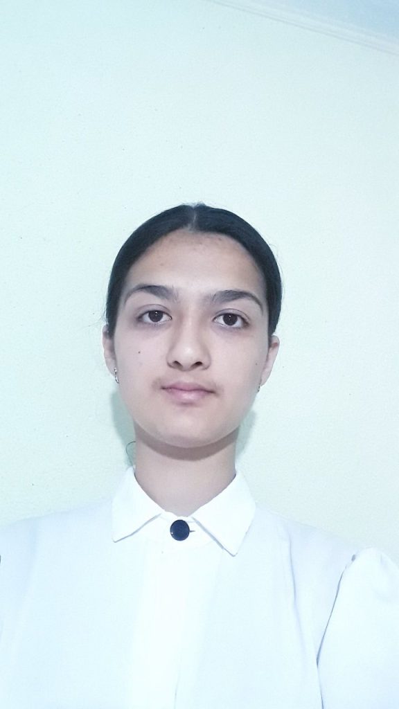 Young Central Asian woman with brown eyes and short brown hair, in a white collared shirt. 
