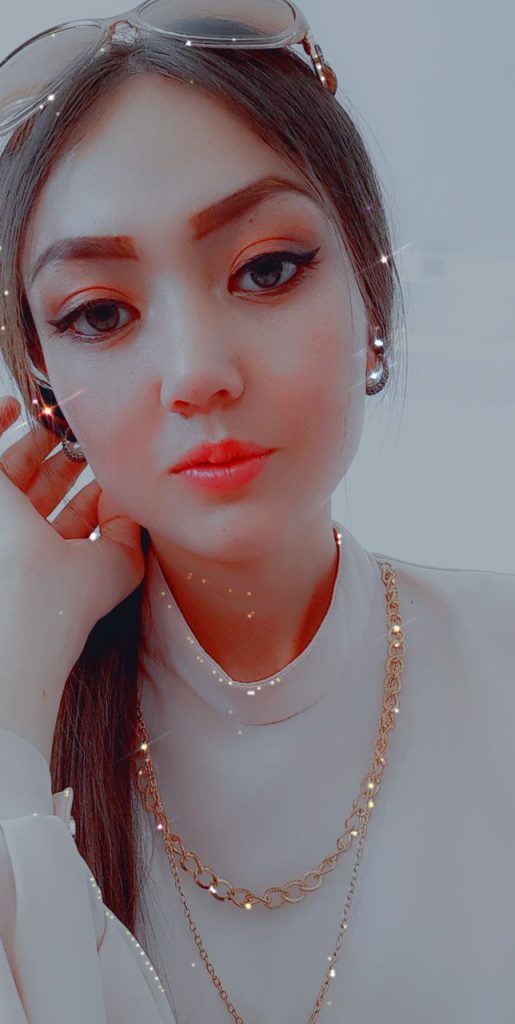Central Asian teen girl with makeup, long dark hair, brown eyes, a gold chain necklace, and a white or cream top. Social media filter that makes her look sparkly. 