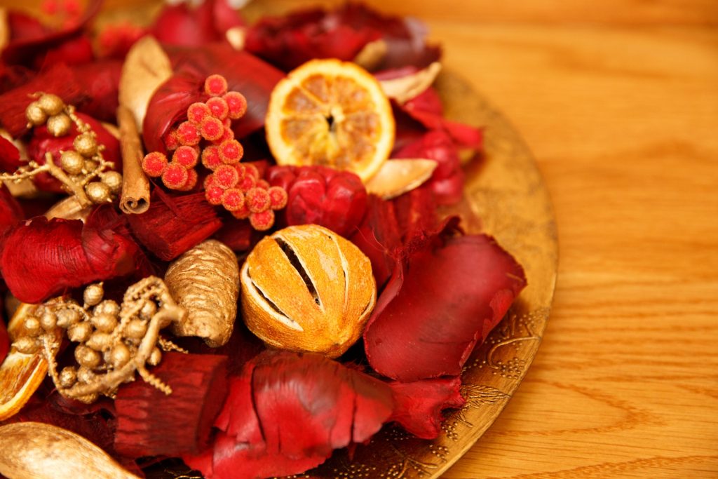 Red and orange holiday potpourri with dried oranges, red berry and flower petals on a wood table