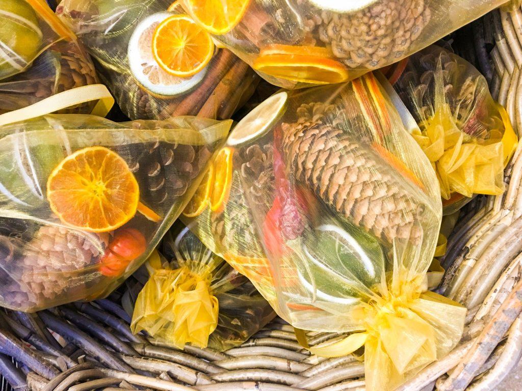 Yellow gauze bags of dried pine cones and citrus slices inside a wicker basket
