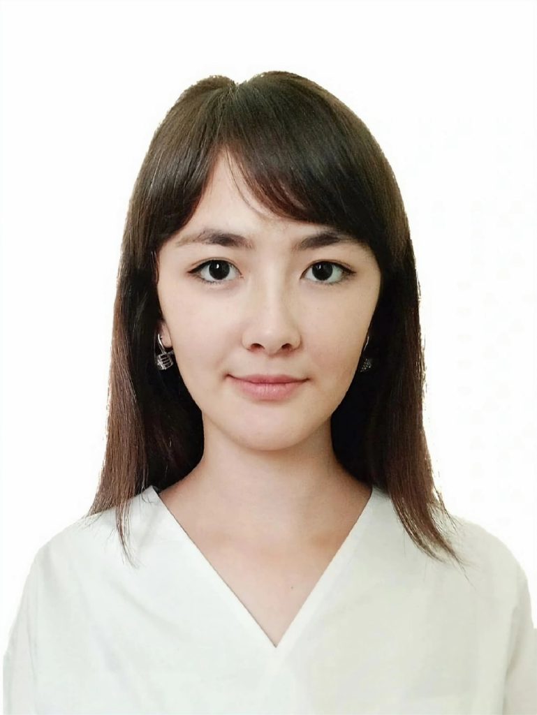 Young Central Asian woman with brown hair, brown eyes, a white blouse and earrings. 