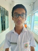 Young South Asian preteen boy with reading glasses, short brown hair, brown eyes and a white collared school uniform shirt.