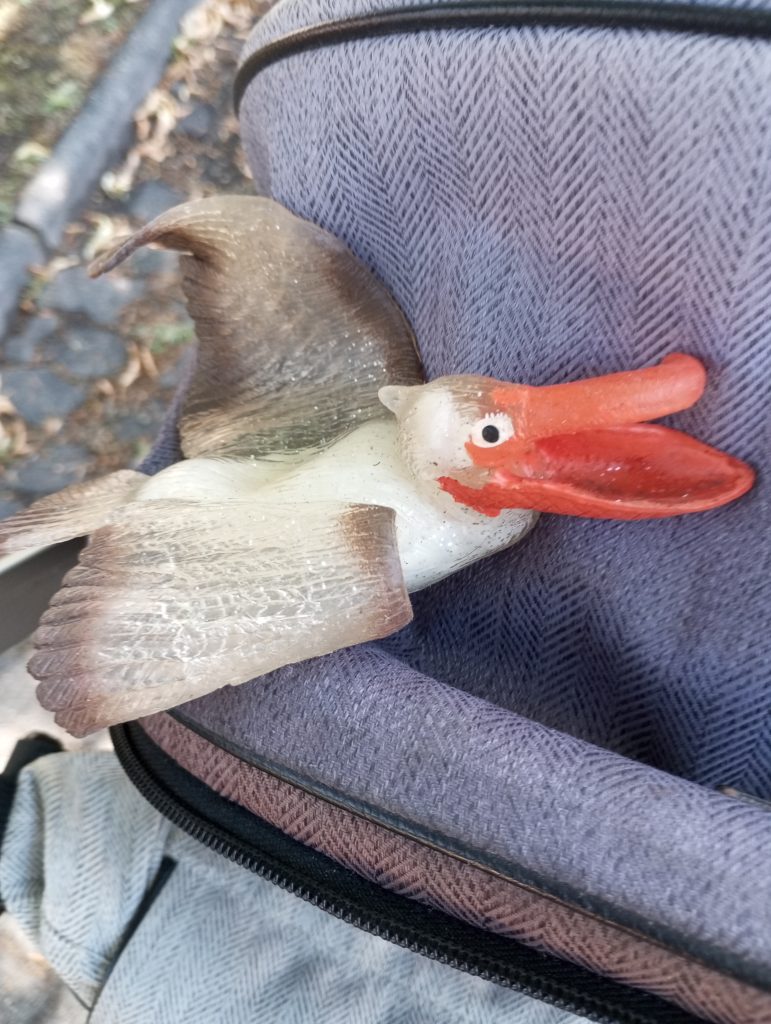 Plastic model duck with a big orange bill on a denim backpack. 