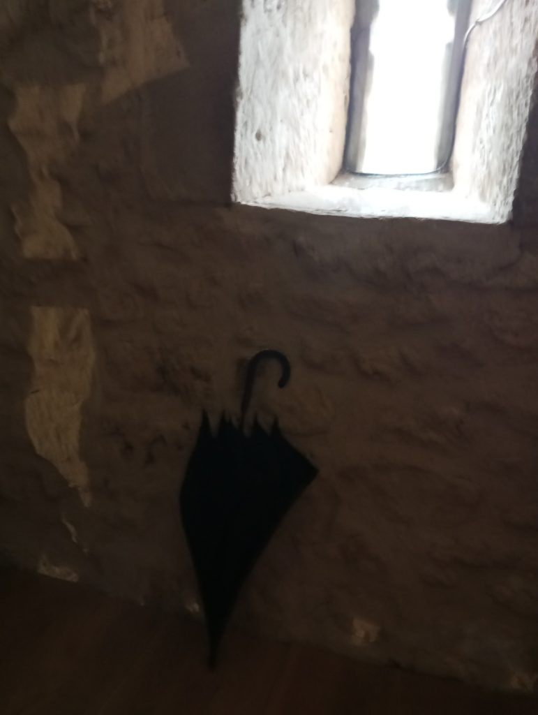 Umbrella in the corner of an alcove in a gray old building. 
