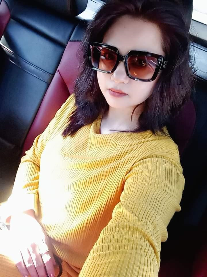 Young South Asian woman with light skin, dark sunglasses, dark shoulder length hair, and a yellow blouse. 