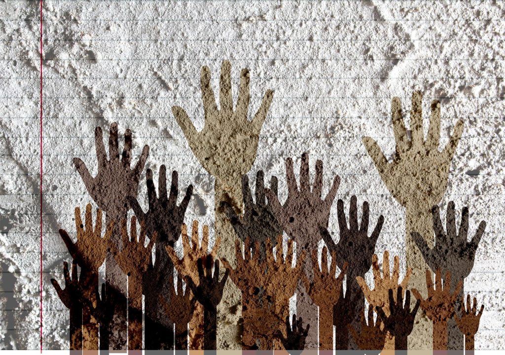 Silhouettes of hands in all skin colors up against the concrete walls. 