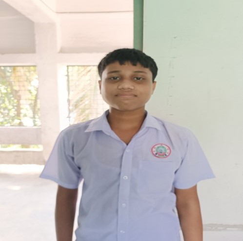Young South Asian preteen boy in a white shirt school uniform and with short brown hair.