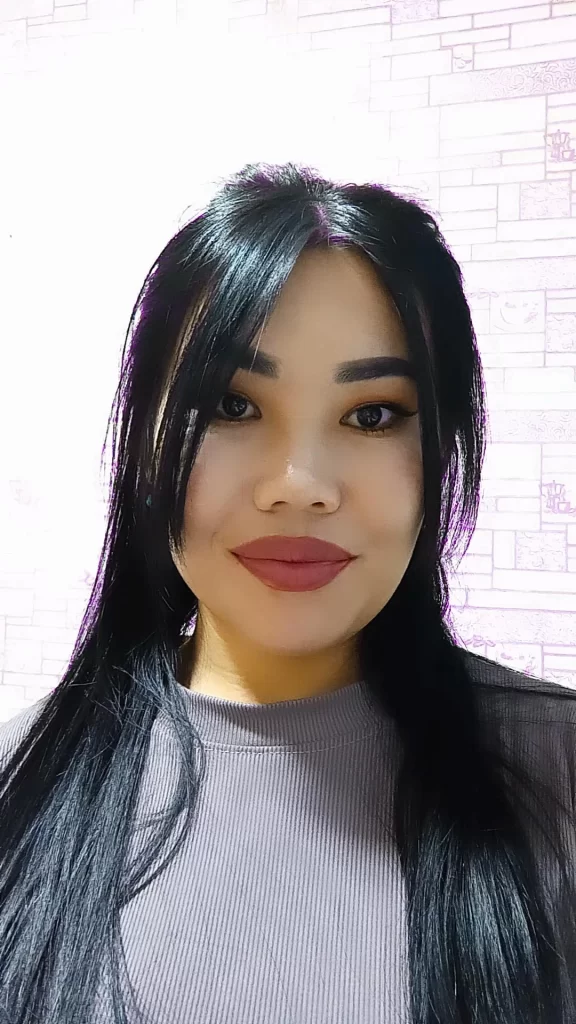 Central Asian teen girl with brown eyes, makeup and lipstick, long straight dark hair, and a grey blouse. 