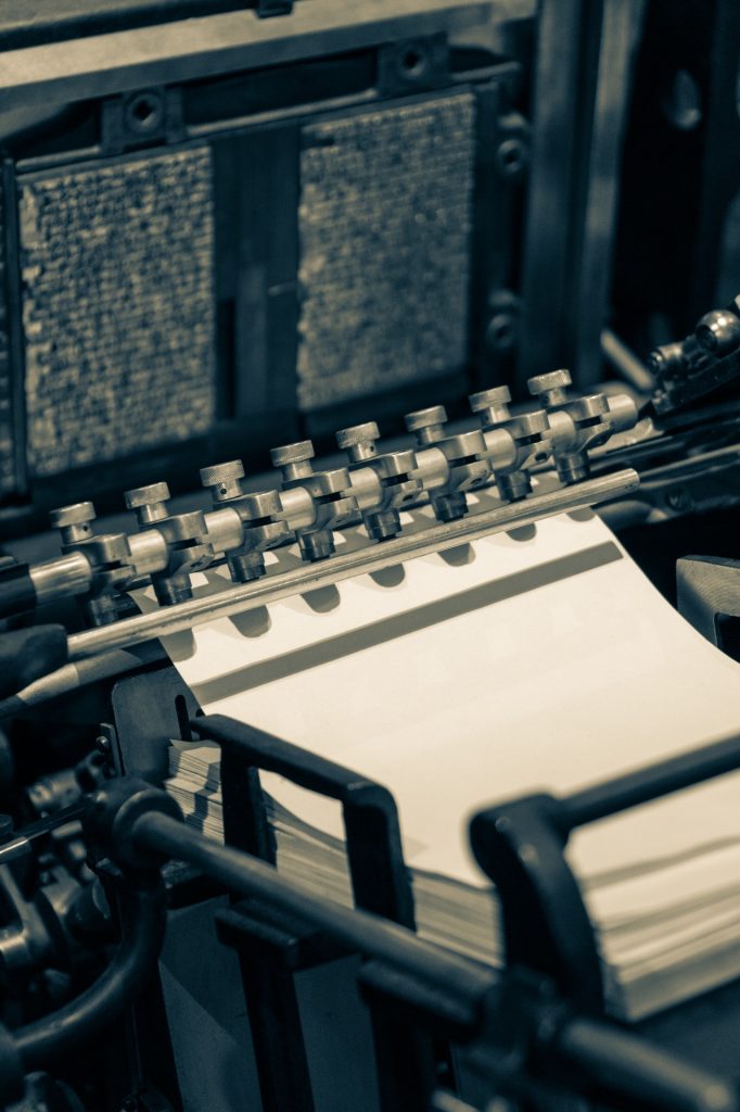 Old style printing press, text and gears and paper in view. 