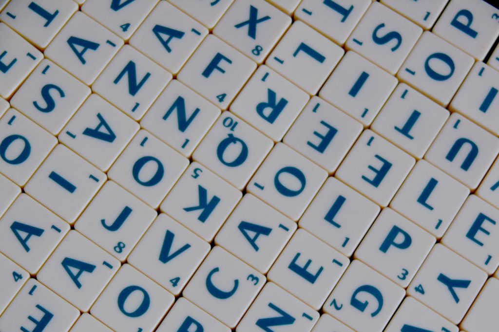 Scrabble tiles with blue letters on white plastic tiles. 