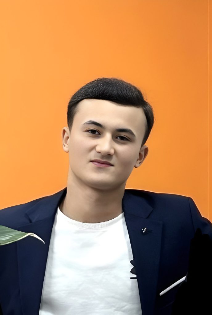 Central Asian teen boy with short brown hair, brown eyes, and a white tee shirt and blue lapel coat. Orange background. 