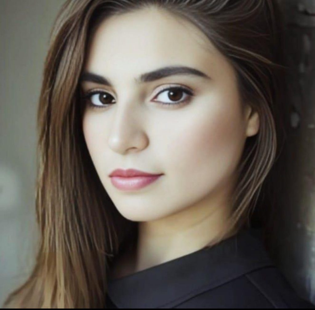Light skinned Pakistani woman with brown eyes and straight brown hair looks out at the camera. She's wearing a black blouse. 