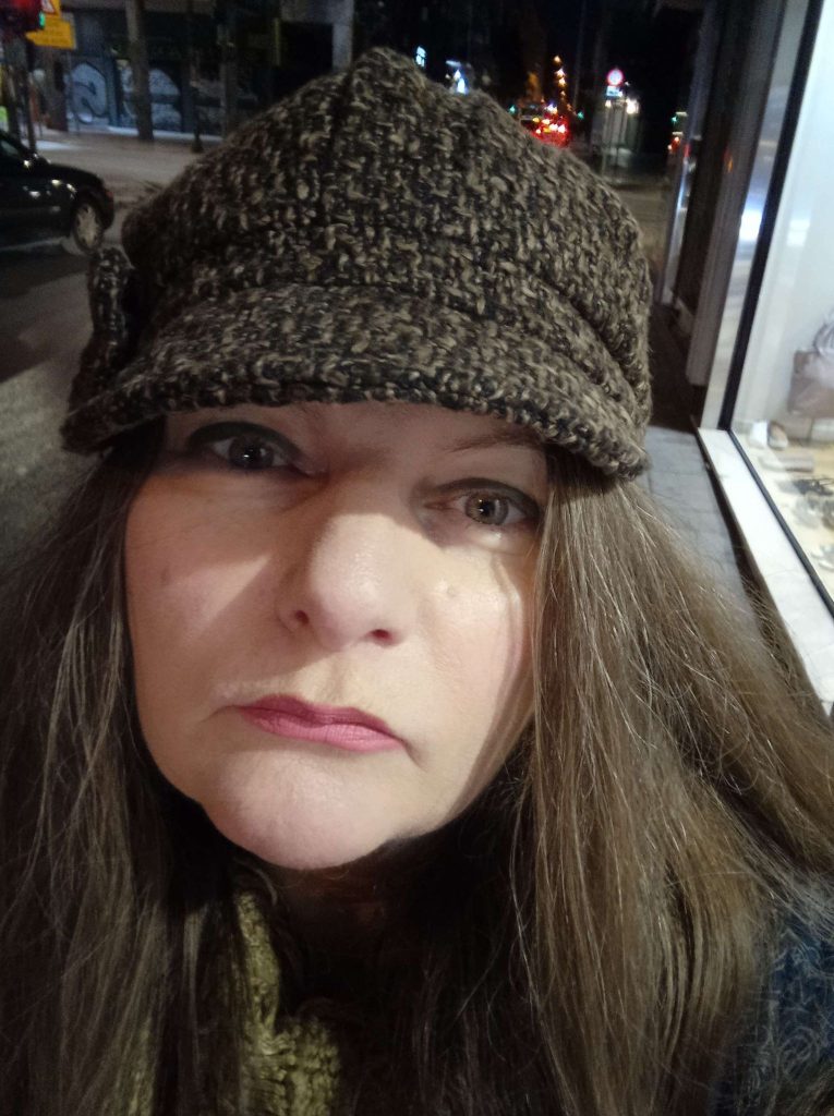 Middle aged light skinned woman with a brown knit cap and long light brown hair. 