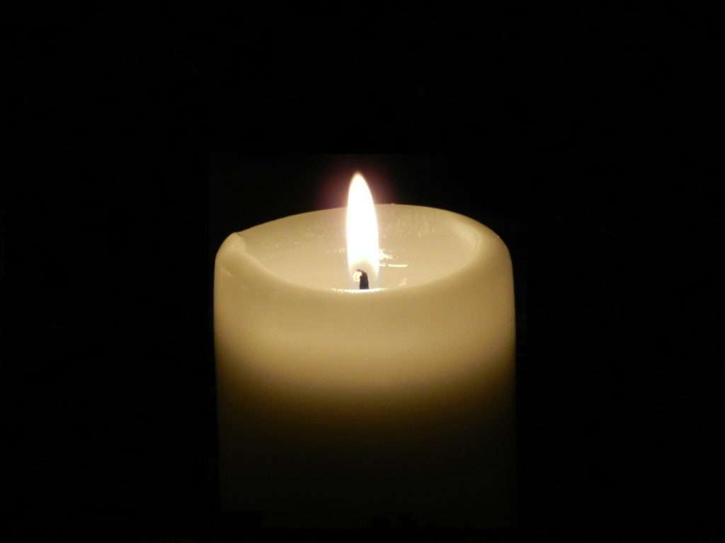 White candle burns against a black background.