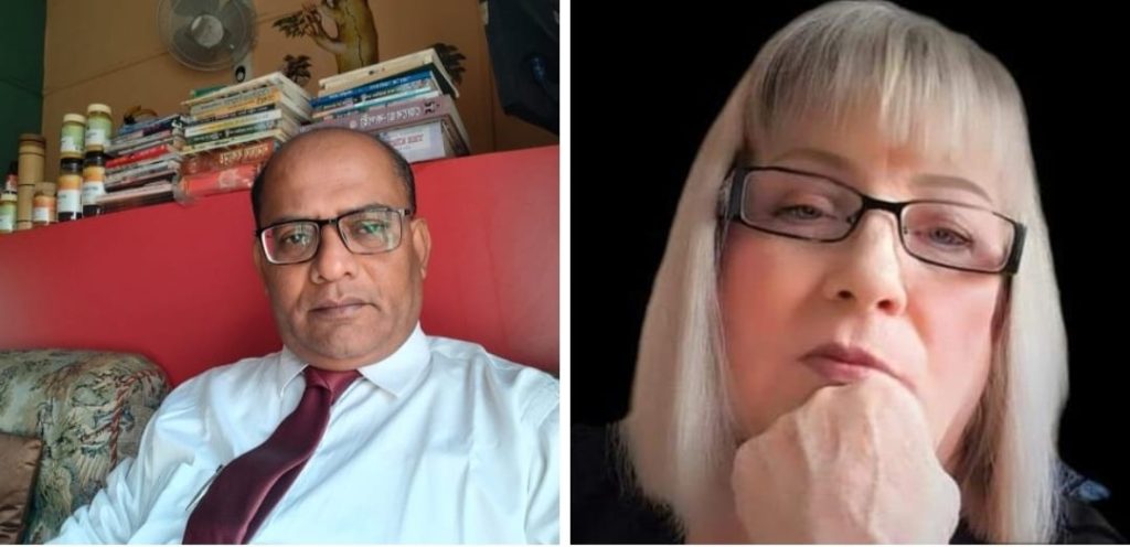 Older middle aged South Asian man with reading glasses and a white collared shirt and dark burgundy tie in a room with a red wall and a stack of books behind him. 

White middle aged woman with reading glasses and very blond straight hair resting her head on her hand.
