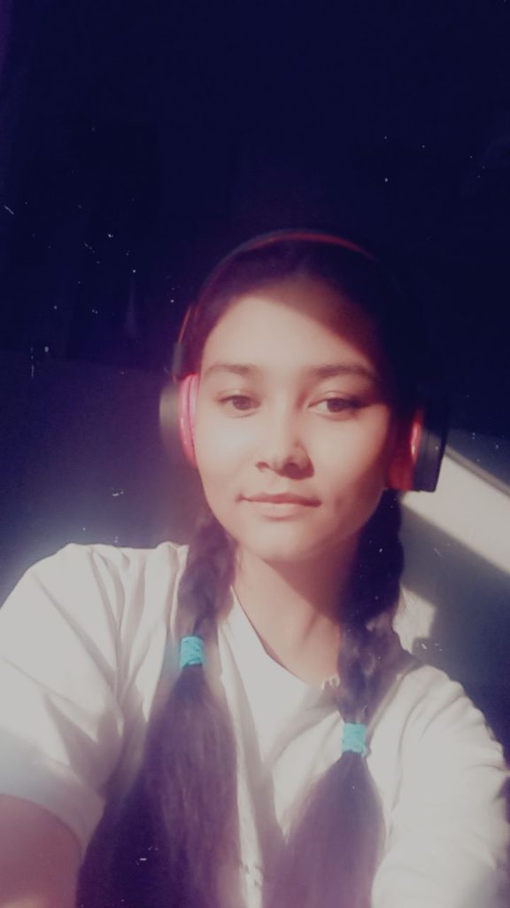 Central Asian teen girl with two black braids, earphones, a white tee shirt, a calm pensive expression, and foggy darkness behind her. 