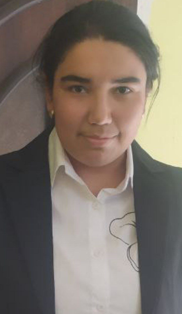 Central Asian teen girl with brown hair and eyes, white collared shirt and black coat. 