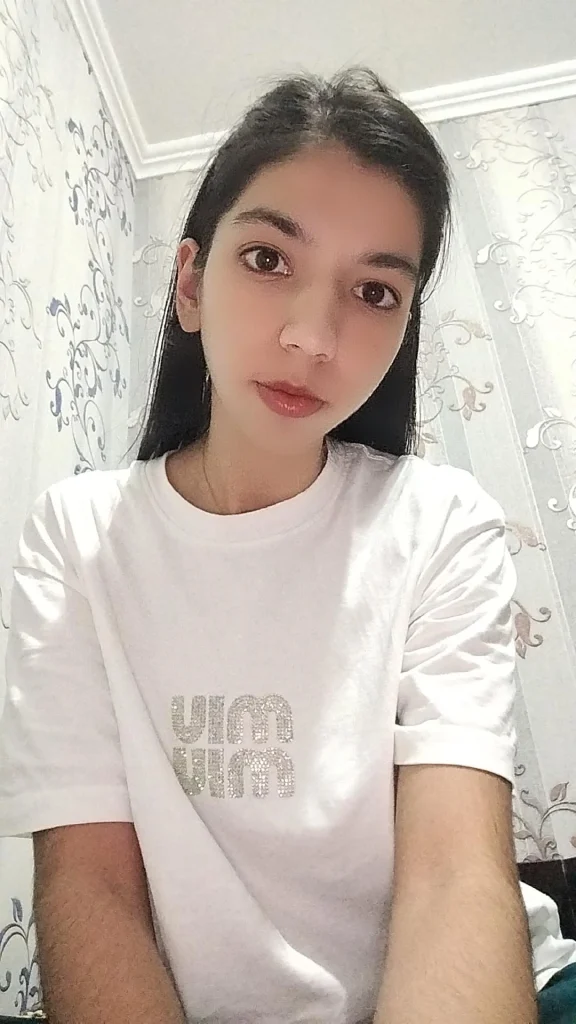 Central Asian teen girl with straight dark hair and brown eyes and a white tee shirt. 