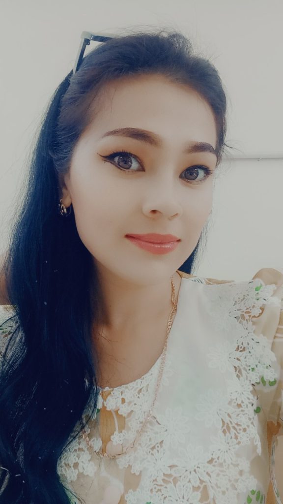 Young Central Asian woman with long dark hair, brown eyes, and a fluffy lace blouse. 