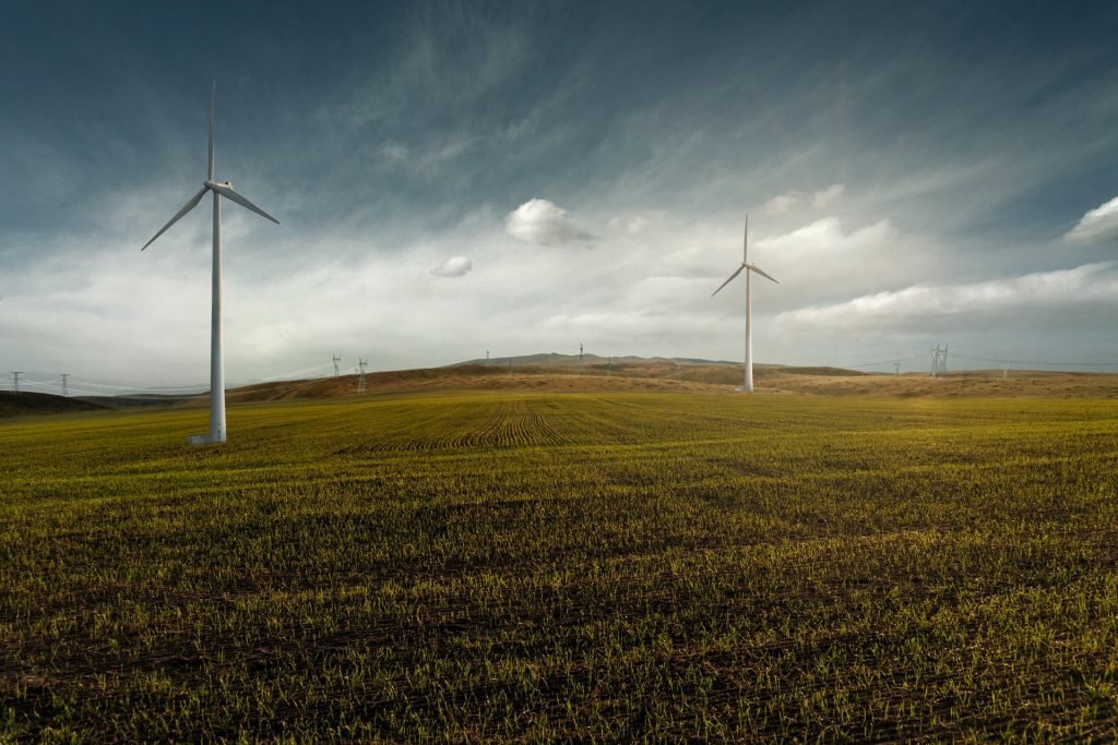 Stylized photo of white windmills in a grassy field on a partly cloudy day. 