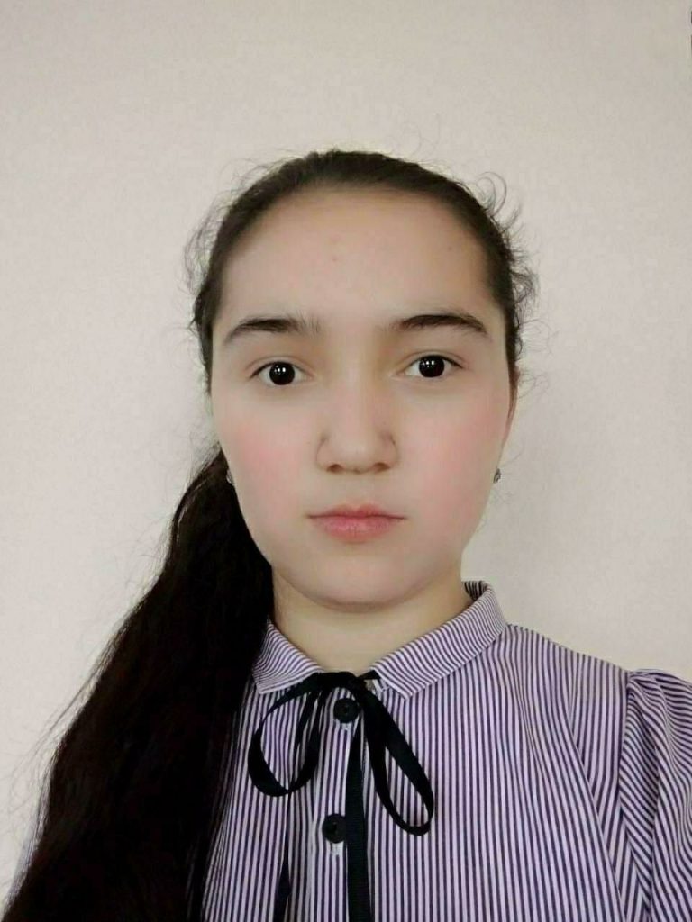 Central Asian teen girl with a long ponytail of dark hair and in a striped blouse with a black tie. 