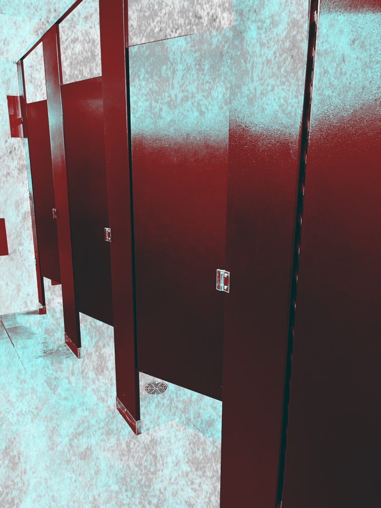 Red toilet stall doors with a blurred green floor. 