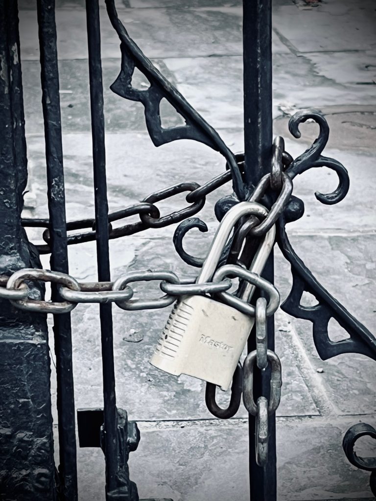 Closeup of a lock and chain on a metal fence. 