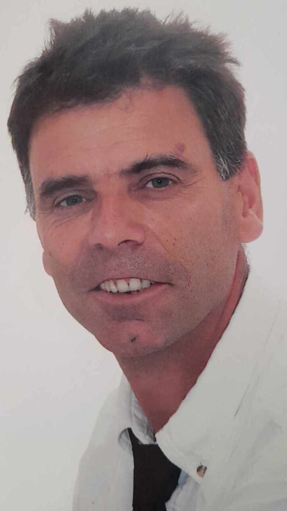 Middle aged white man with a clean shaven face, brown hair and eyes in a collared shirt. 