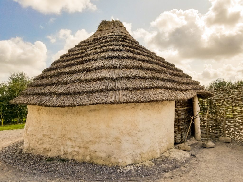 Small mud house with a roof of stacked reeds and a wooden door. From Neolithic times near Stonehenge. 