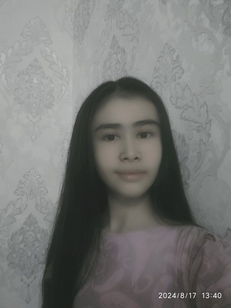 Central Asian teen girl with long dark hair and brown eyes in a pink patterned blouse. 