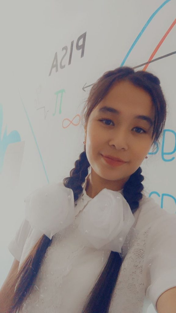 Central Asian teen girl with dark hair in braids and brown eyes and a white frilly blouse. 