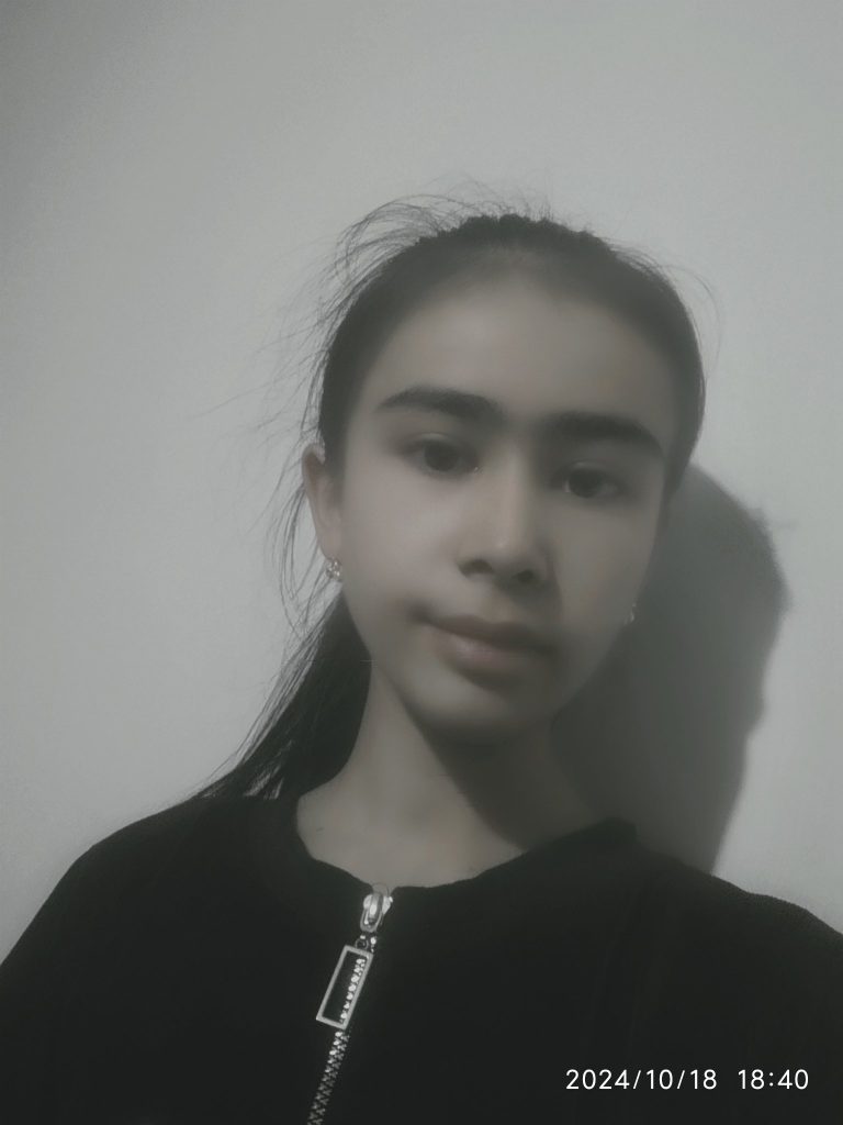 Teen Central Asian girl with long dark hair, brown eyes, and a black jacket with a zipper.