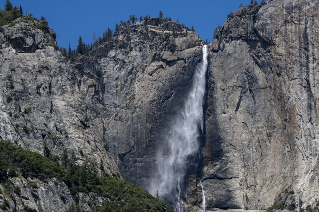 Yosemite's Bridalveil Falls, water descending many hundreds of feet down a gray rocky cliff face. 