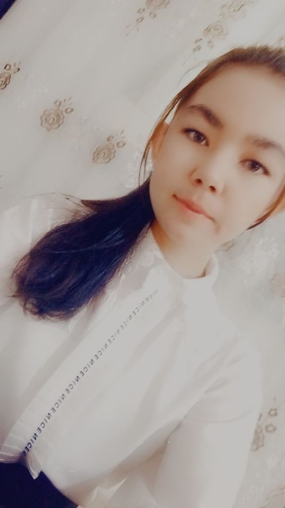 Central Asian teen girl with long straight dark hair in a ponytail and a white ruffled blouse. 