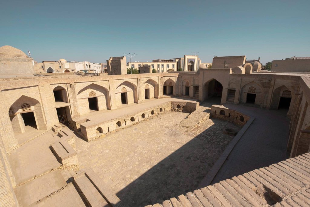 Uzbek historical monument of Bukhara. Stone city plaza with doorways and stairs and a skyline. 