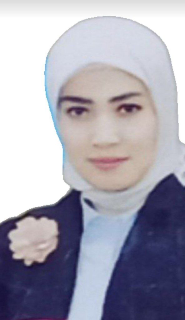 Young Uzbek woman in a white headscarf and a blue top with a pink rose on her chest. 