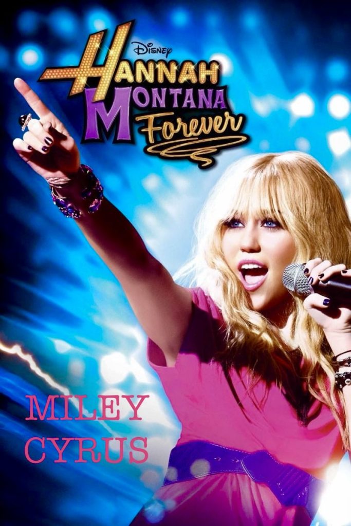 Photo of blonde Miley Cyrus in a pink shirt singing into a microphone. She's got painted nails and bracelets and a blue background. 