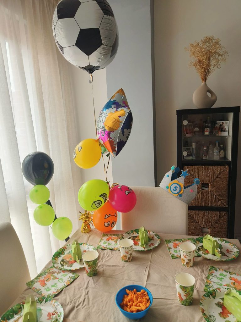 Closeup of balloons in a house near curtains. Multicolored balloon arrangement, one balloon is a soccer ball. 