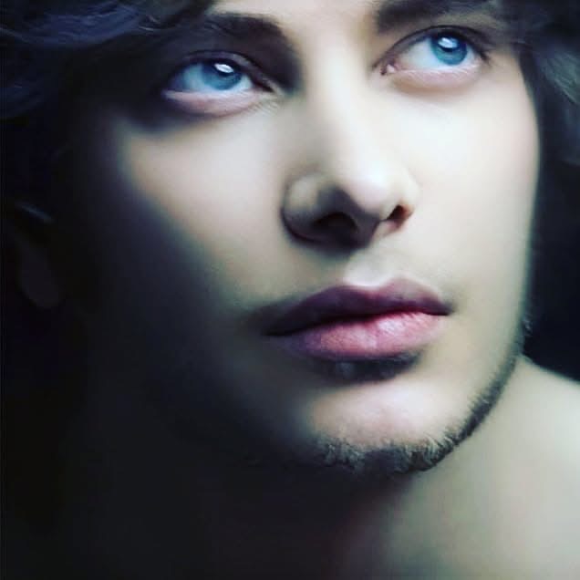 Young man photographed with dreamy eyes and hazy outlines. He's got blue eyes and dark hair.