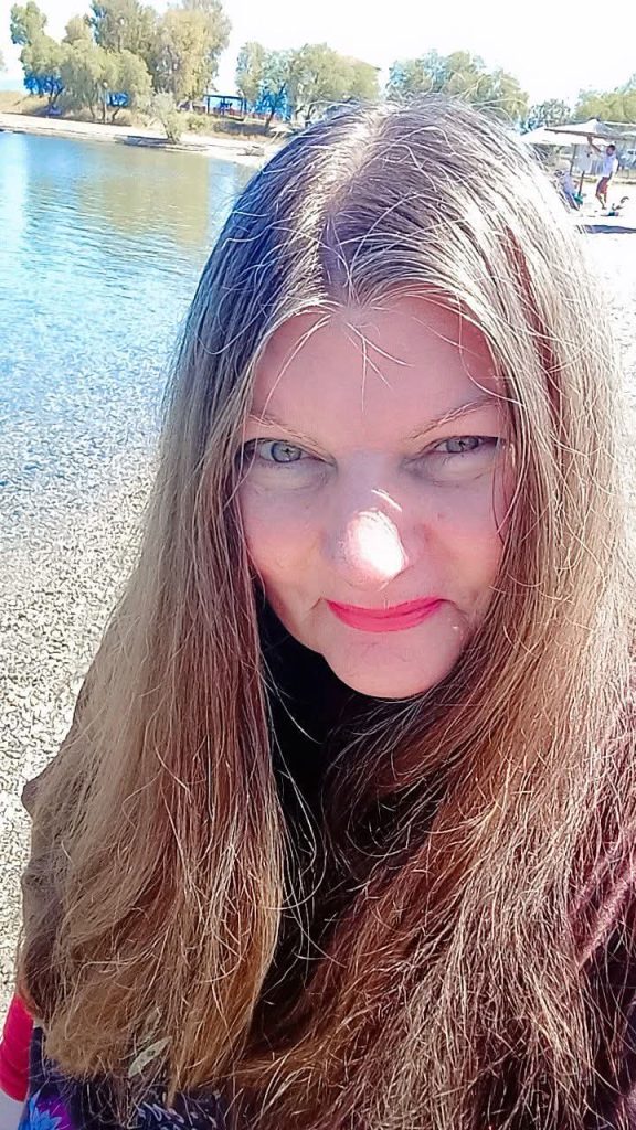 Middle-aged, light-skinned European woman with light blue eyes, light brown hair, and a black turtleneck sweater.