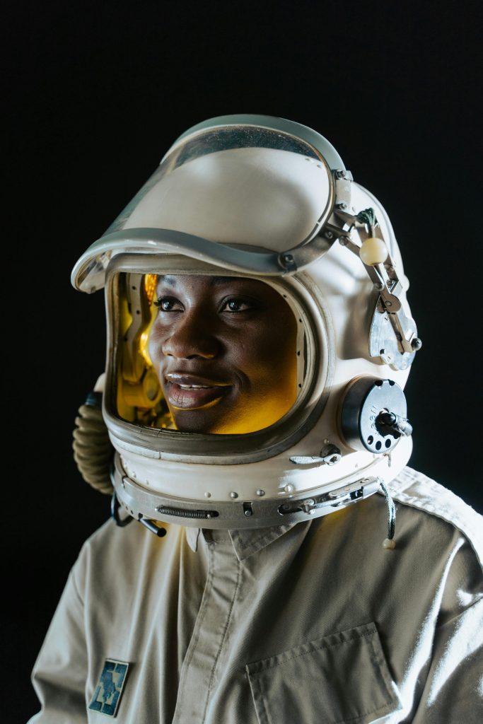 Young Black woman in a spacesuit with a big smile.